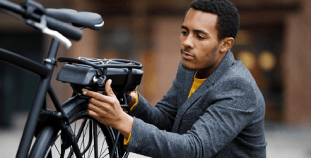 Jovem verifica bicicleta elétrica Jovem verifica a sua bicicleta elétrica antes de iniciar viagem